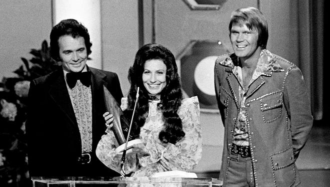 Loretta Lynn accepts the Female Vocalist of the Year award at the seventh annual CMA Awards show at the Grand Ole Opry House on Oct. 15, 1973. Looking on are presenters Merle Haggard, left, and Glen Campbell.