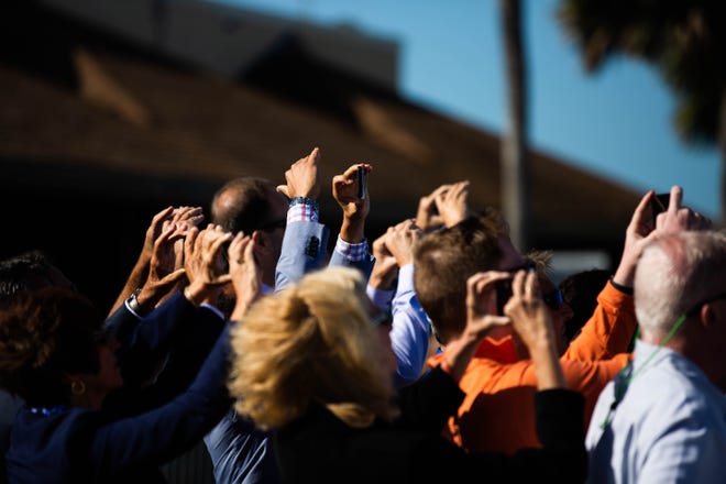 As Air Force Two lands, viewers hold up phones to document its landing at the Naples Airport on Thursday, March 28, 2019.