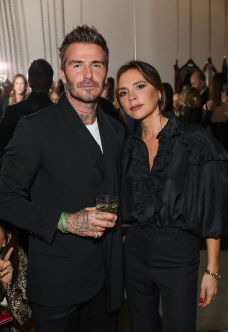Dressed in this black look from her own collection, Victoria Beckham Resort 2020, she poses with her husband on Sept. 30, 2019.
