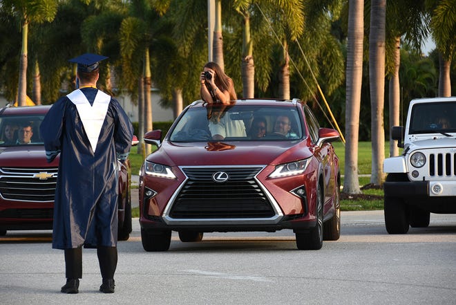 Graduate Savannah Heierl snaps a fellow grad from her car. Marco Island Academy, Marco Island's charter high school, held a "drive-in" graduation ceremony for their 47 graduating seniors Friday evening in the parking lot at Veterans' Community Park.