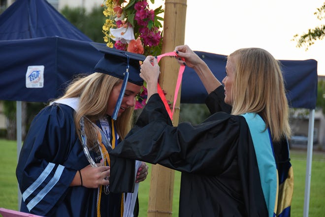 MIA Principal Melissa Scott gives the Principal's Award and aa hug to graduate Lauren Faremouth. Marco Island Academy, Marco Island's charter high school, held a "drive-in" graduation ceremony for their 47 graduating seniors Friday evening in the parking lot at Veterans' Community Park.