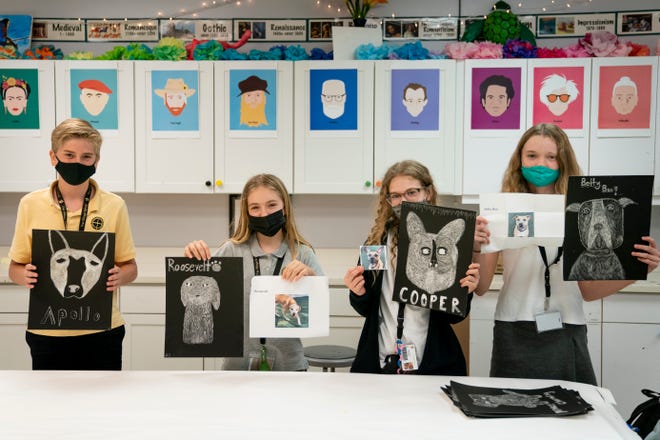 From left to right, Alek Hiester, Amelia Delate, Ava Corbin, and Keira Brady hold up their scratch art dog portraits at The Village School of Naples on Monday, January 25, 2021.