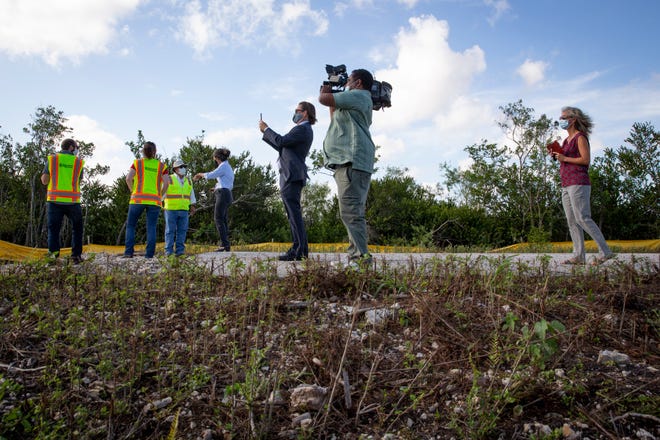 Officials and members of the media watch an excavator remove roadbed from Old Tamiami Trail, west of Miami on Tuesday, March 30, 2021.
